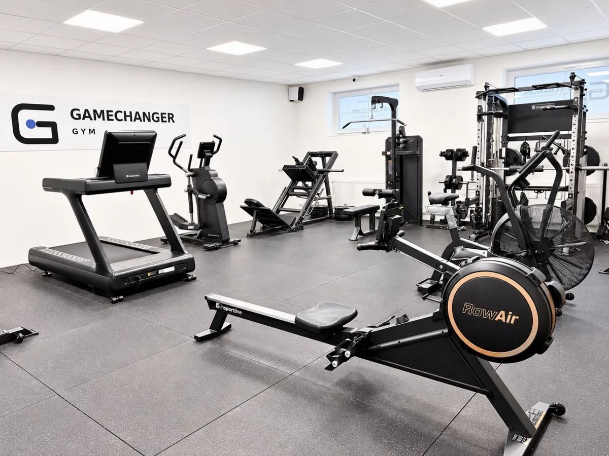 Celkový pohled do GameChanger Gym s běžeckým pásem, veslovacím trenažérem a silovými stroji